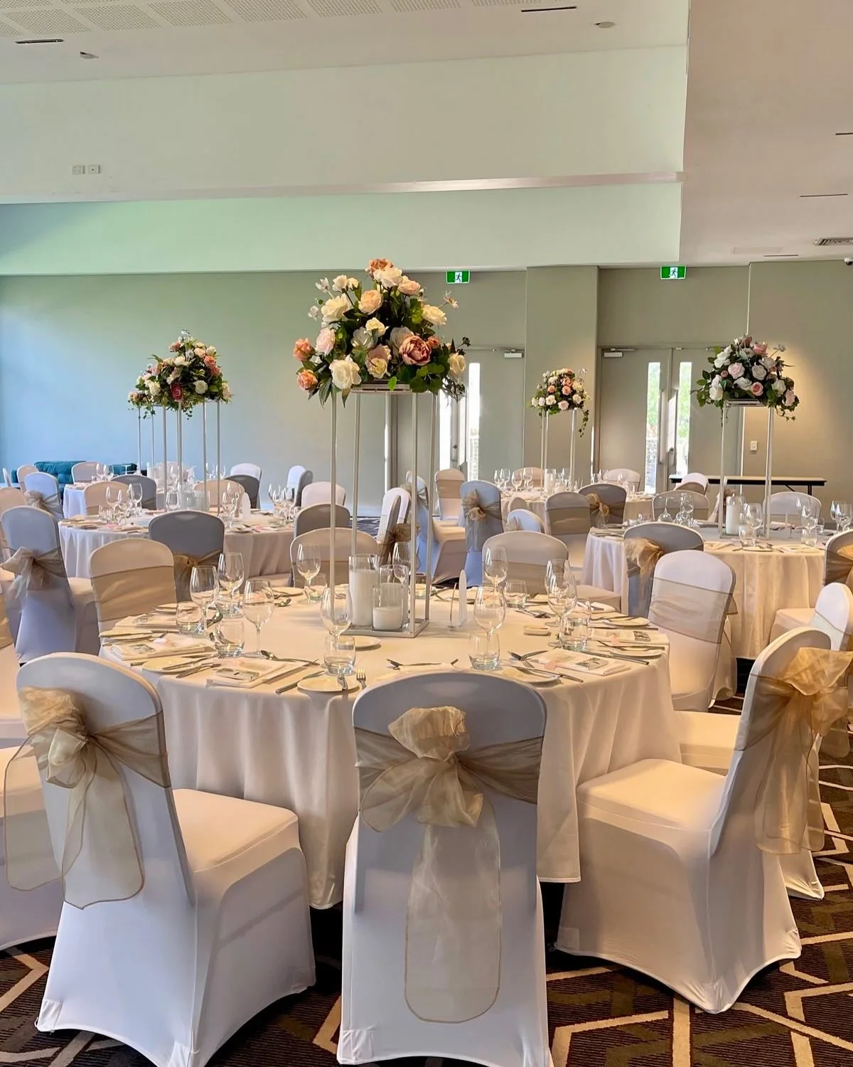 Salle de réception décorée avec arches et centres de table fleuris